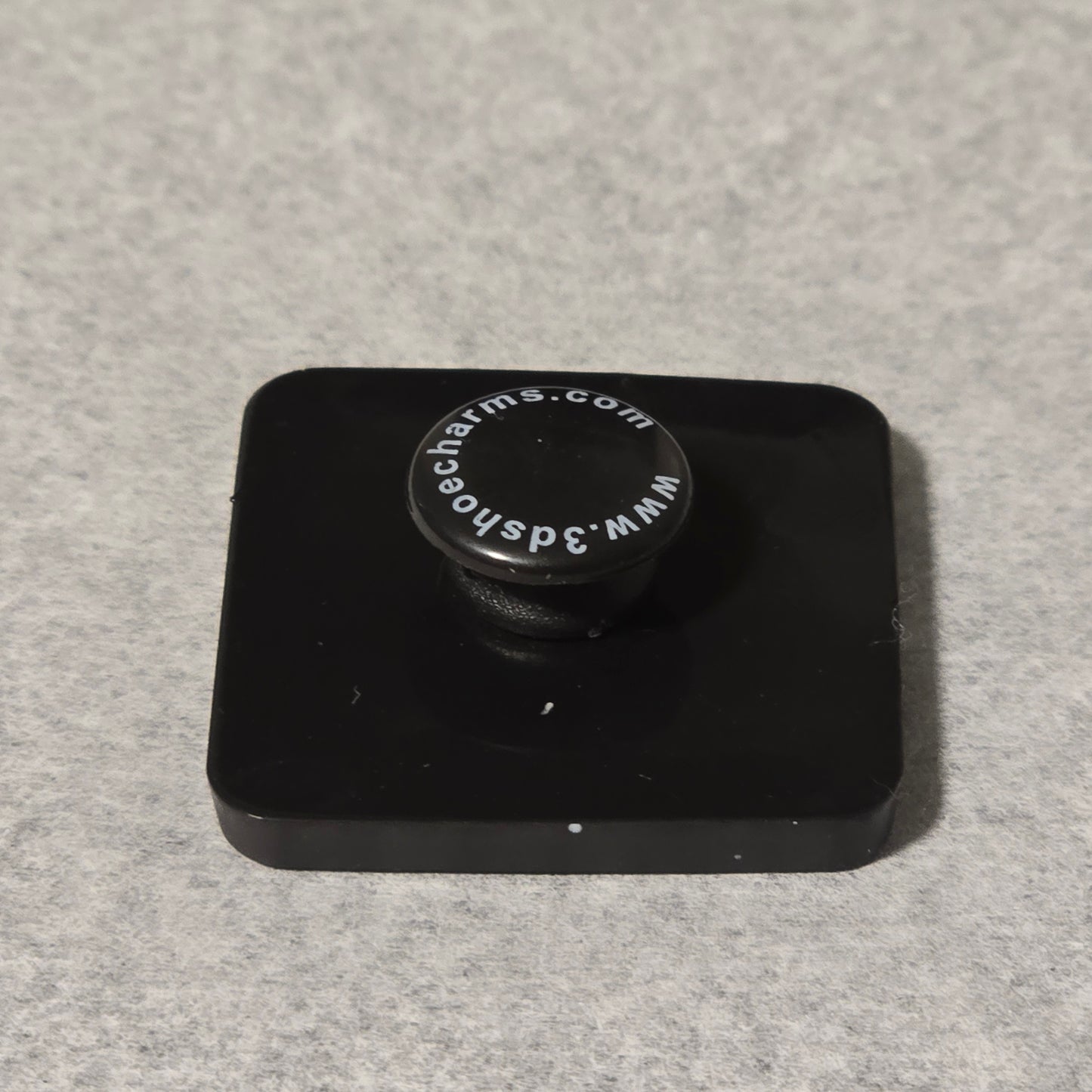 Black square object with a circular component on a gray background