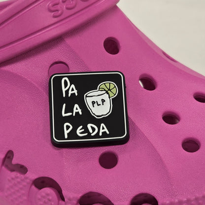 Pink croc shoe with a black and white logo on a white background