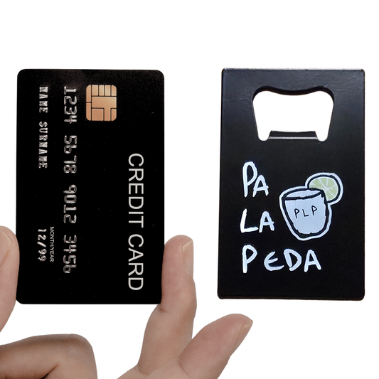 Black card with bottle opener and 'Pa La Peda' design held by a hand.