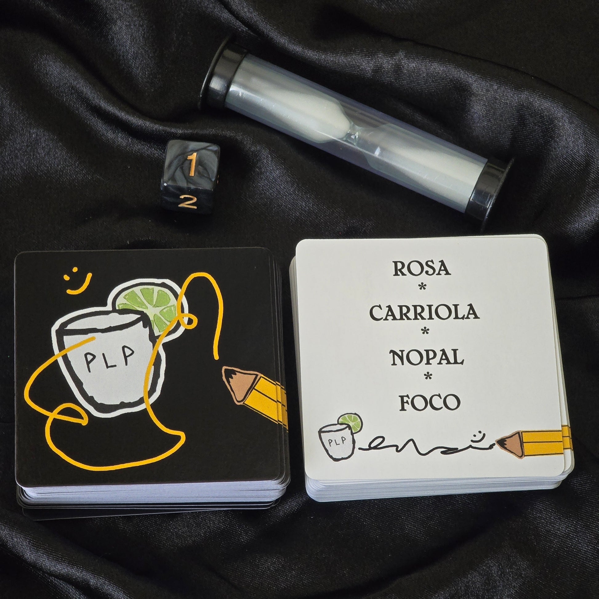 Two cards with illustrations and text on a black fabric background and dice and sand timer