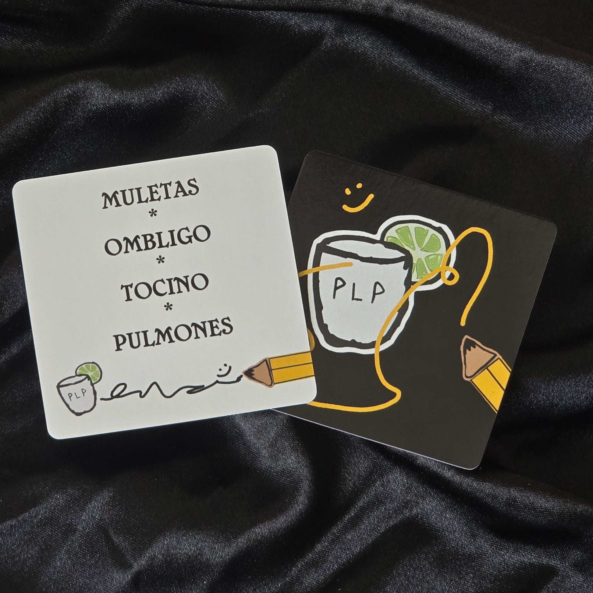 Two cards with illustrations and text on a dark fabric background