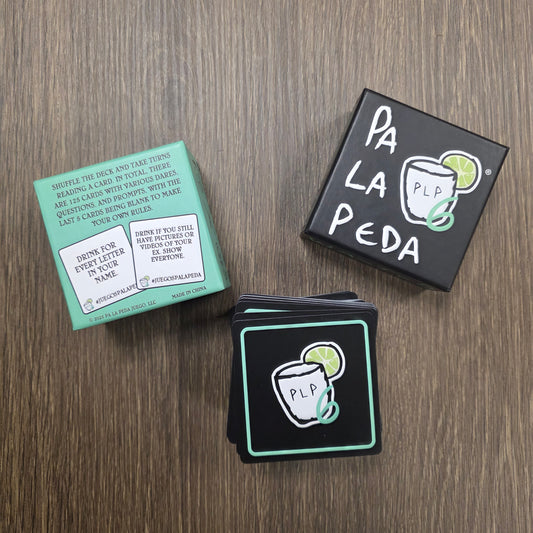 Packaging and cards with 'Pa La Peda' branding on a wooden surface